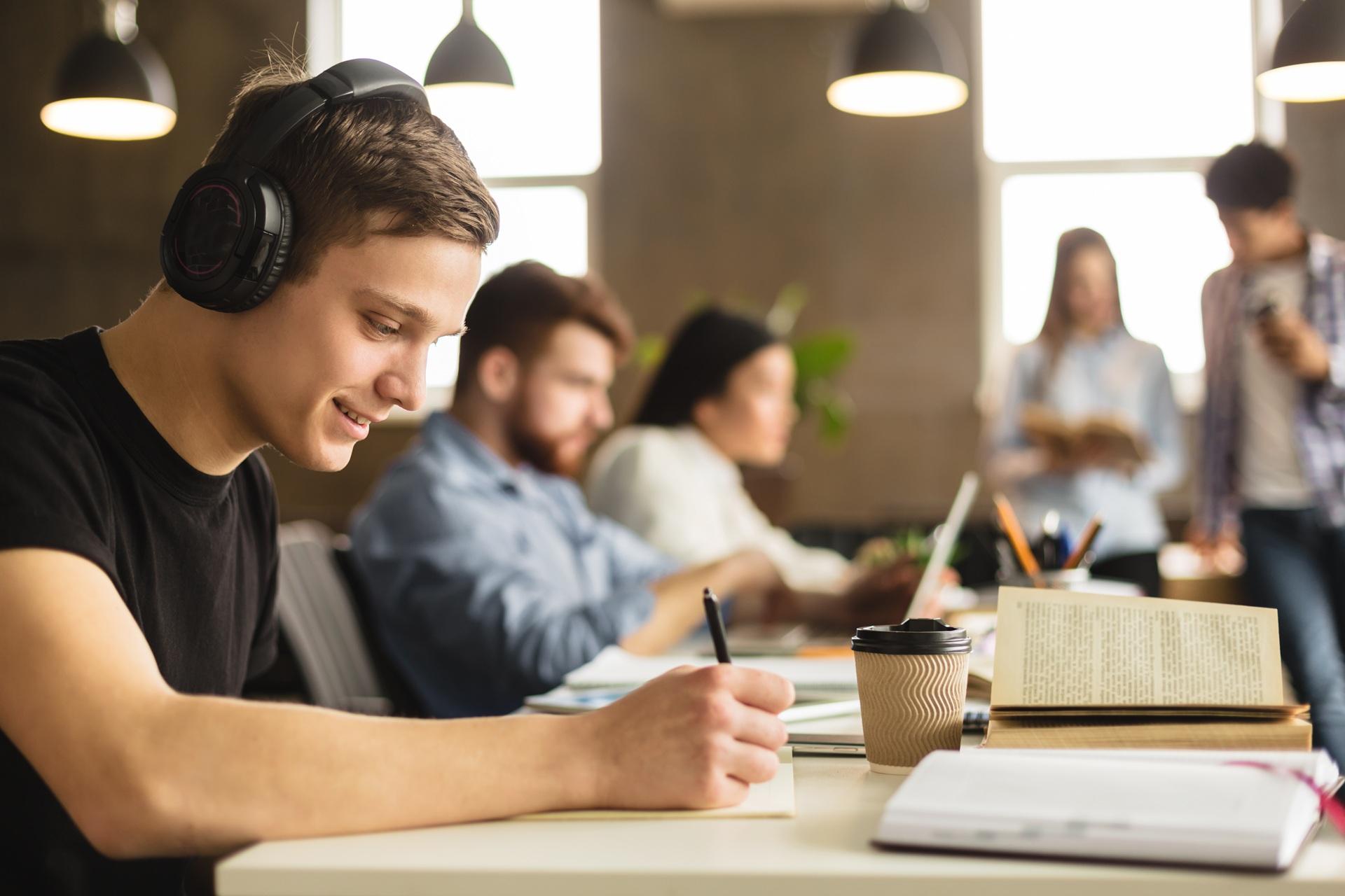 Student schreibt mit Kopfhörern in Lerngruppe | Ghostwriter Bachelorarbeit